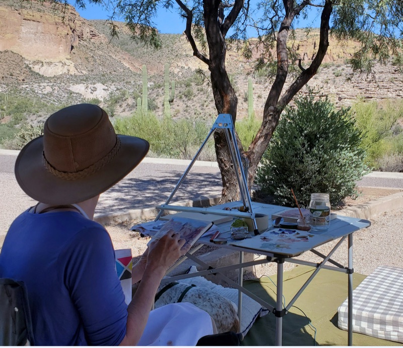 Trisha painting plein air at Tortilla Flat State Park, Arizona — saguaros and red rock walls in the distance