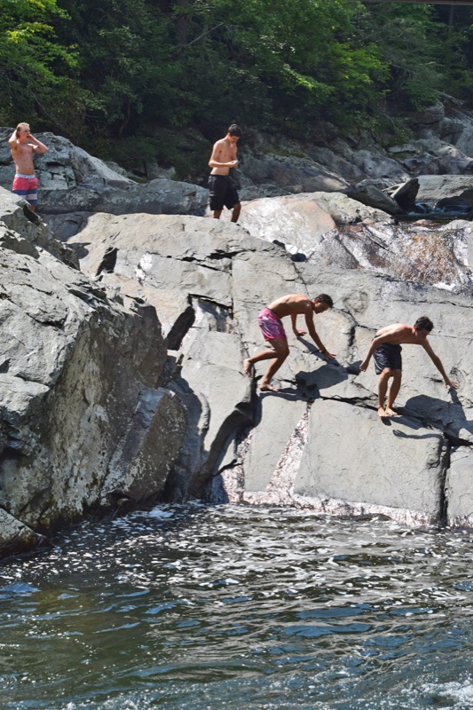 Four boys out on the massive gray boulders above the pool at The Sinks, picking their way across the sunlit rock