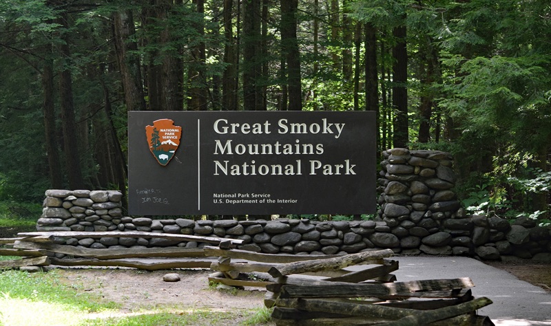 The Great Smoky Mountains National Park entrance sign, set on a stacked-stone base among tall forest